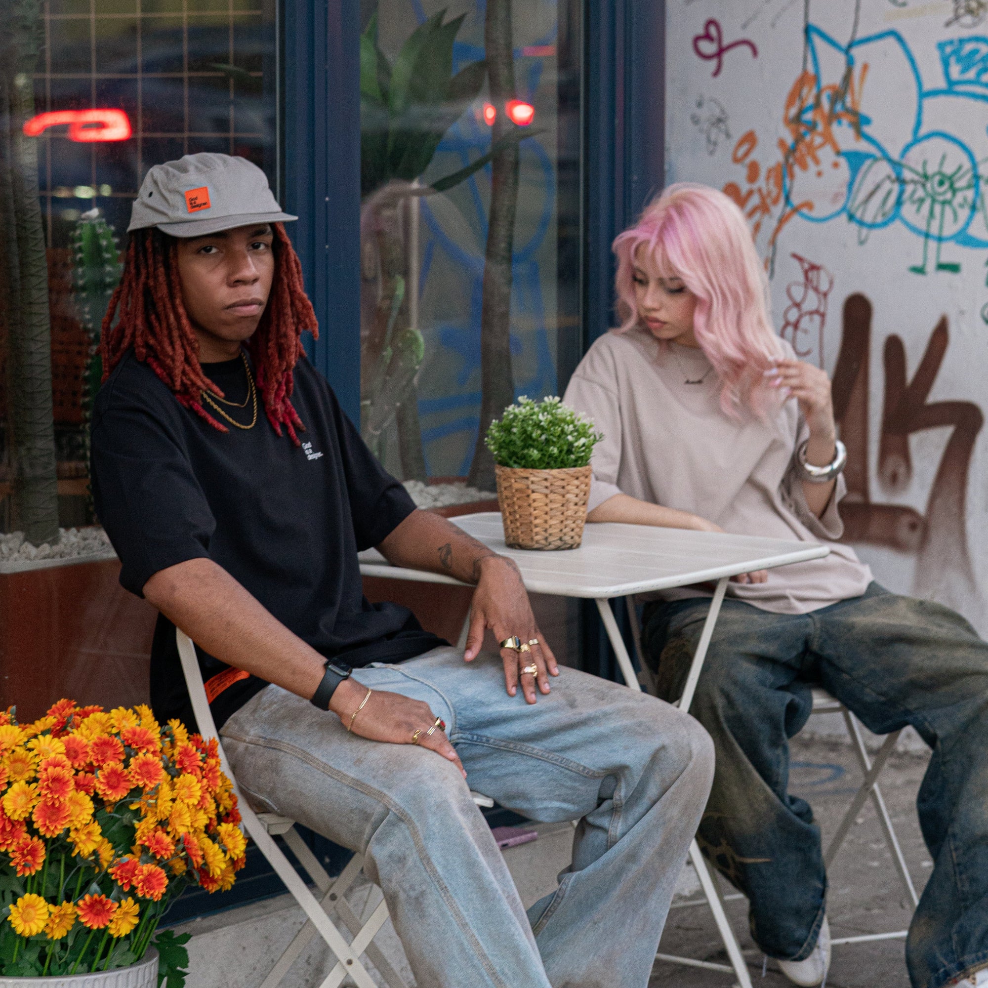 Two people sitting at a table with graffiti on the wall behind them