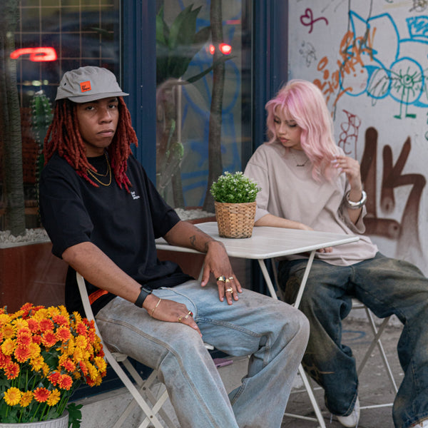 Two people sitting at a table with graffiti on the wall behind them
