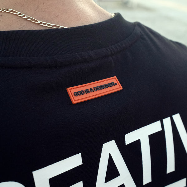 Black shirt with God is a designer orange patch and white text, featuring a gold chain.