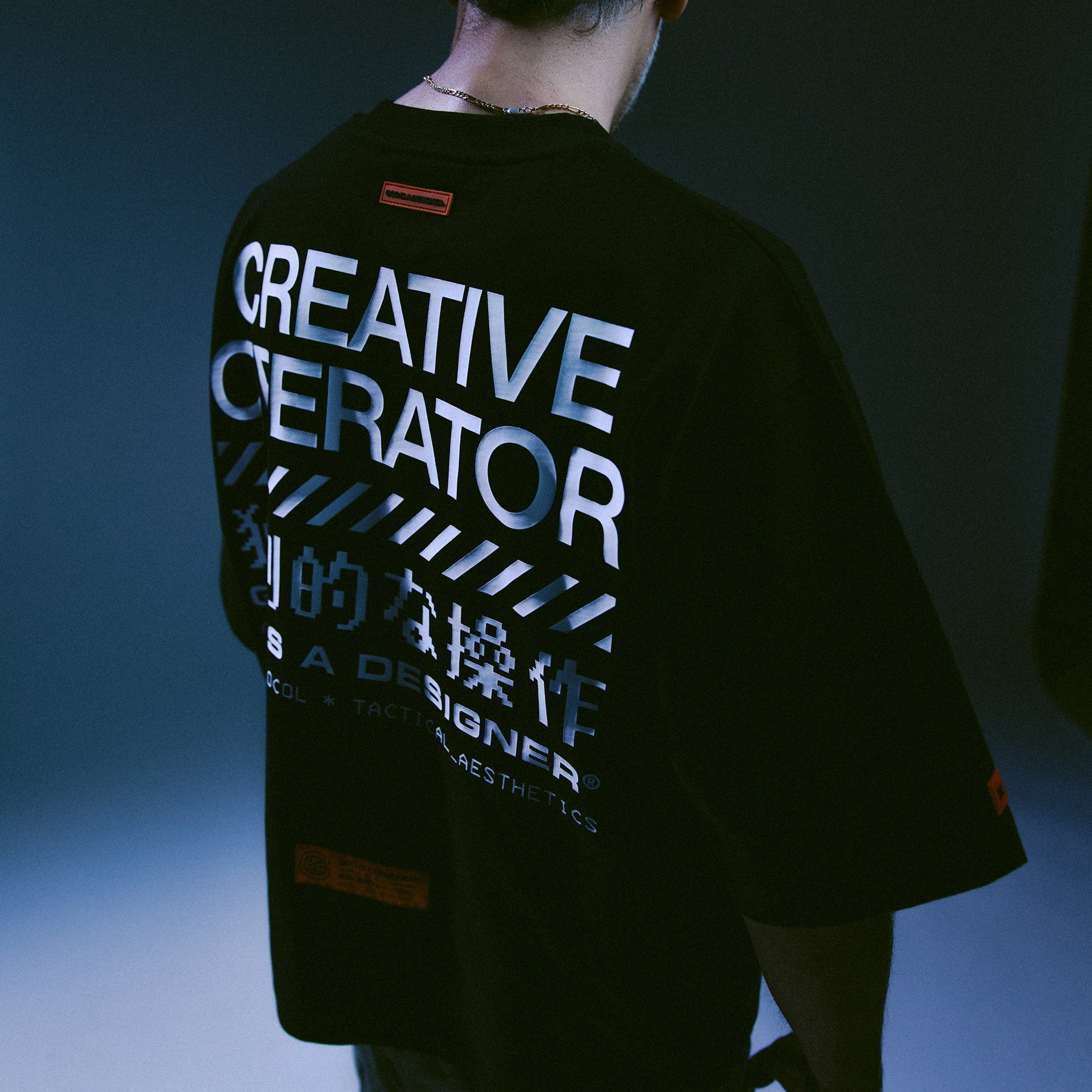 Person wearing a GIAD Creative Operator black t-shirt with text on the back against a dark background