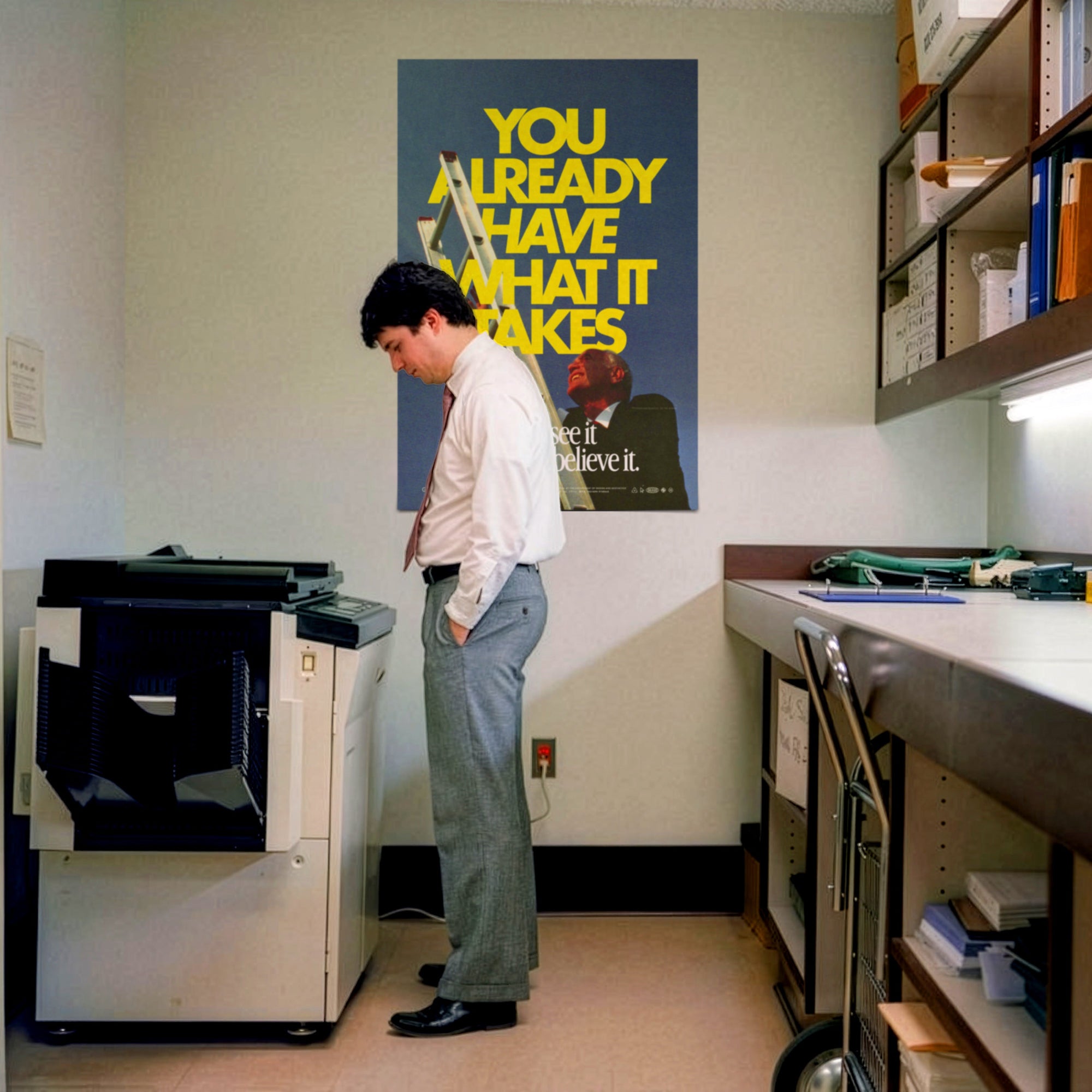 Person using a printer in an office setting with motivational poster on the wall.